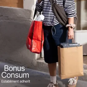 Persona amb bosses de la compra davant d’un aparador, cartell "Bonus Consum, Establiment adherit"